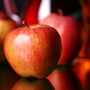 Apples and pitcher with juice against red background