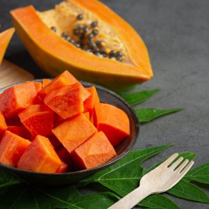 Fresh papaya, cut into pieces, put on a black plate.