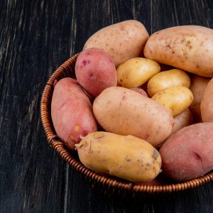 side view of potatoes in basket on wooden background with copy space