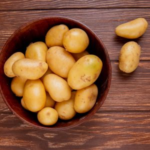 top view of potatoes in bowl on wooden background